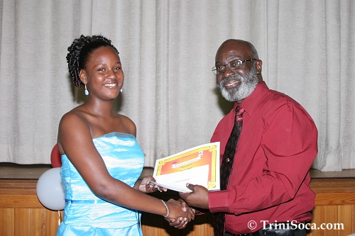 Head of Community Relations for Petrotrin, Rudolph Thomas presents a cash prize to Victoria Cooper